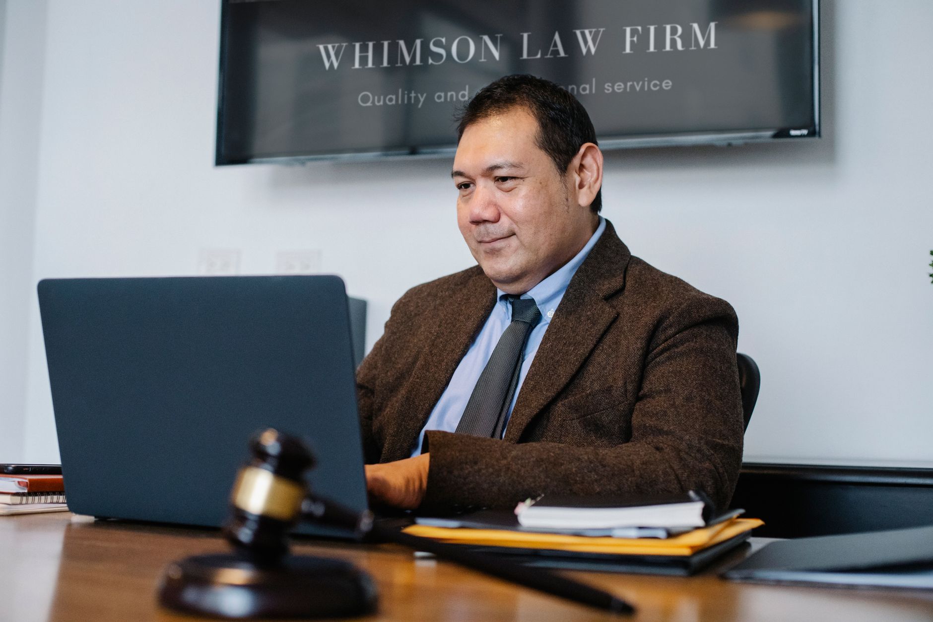 Experienced middle aged ethnic happy male working with netbook at table with judge hammer