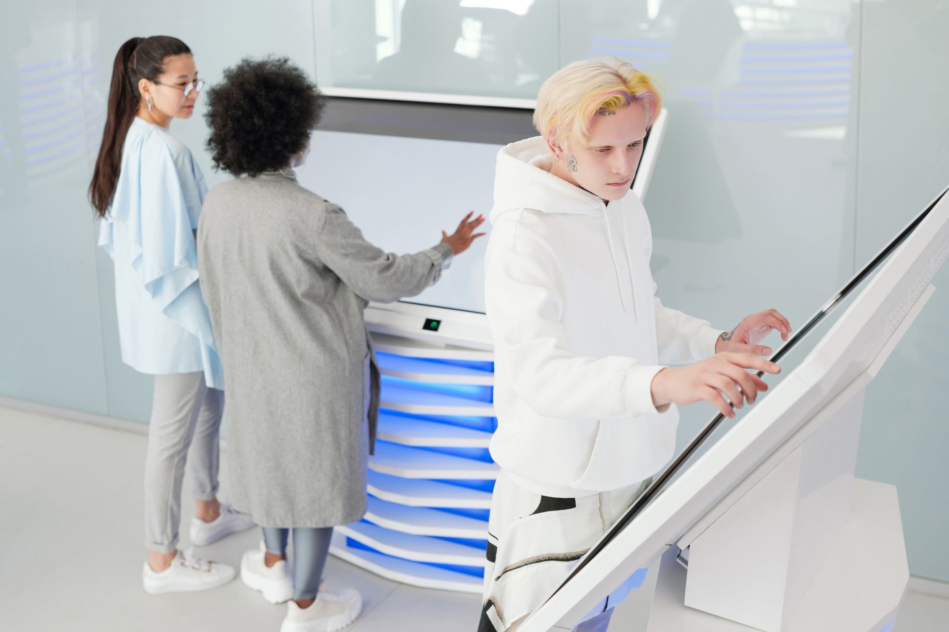 Diverse group interacting with large futuristic touchscreens in a modern tech environment.