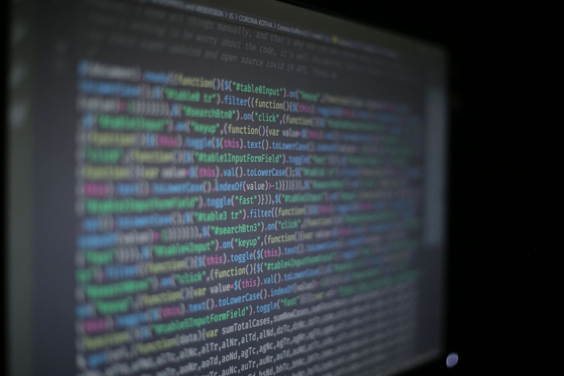 Close-up of colorful programming code on a blurred computer monitor.