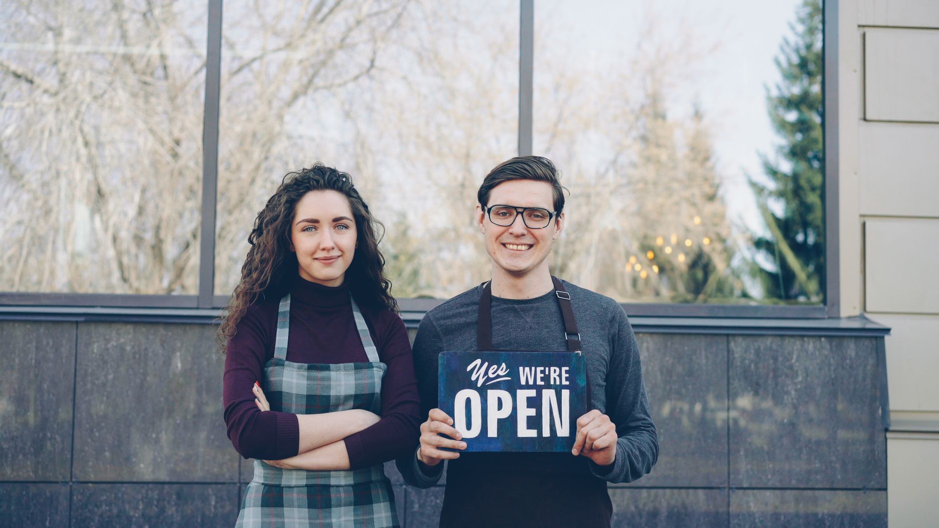 Two startup founders standing outside their first shop, celebrating their first customers