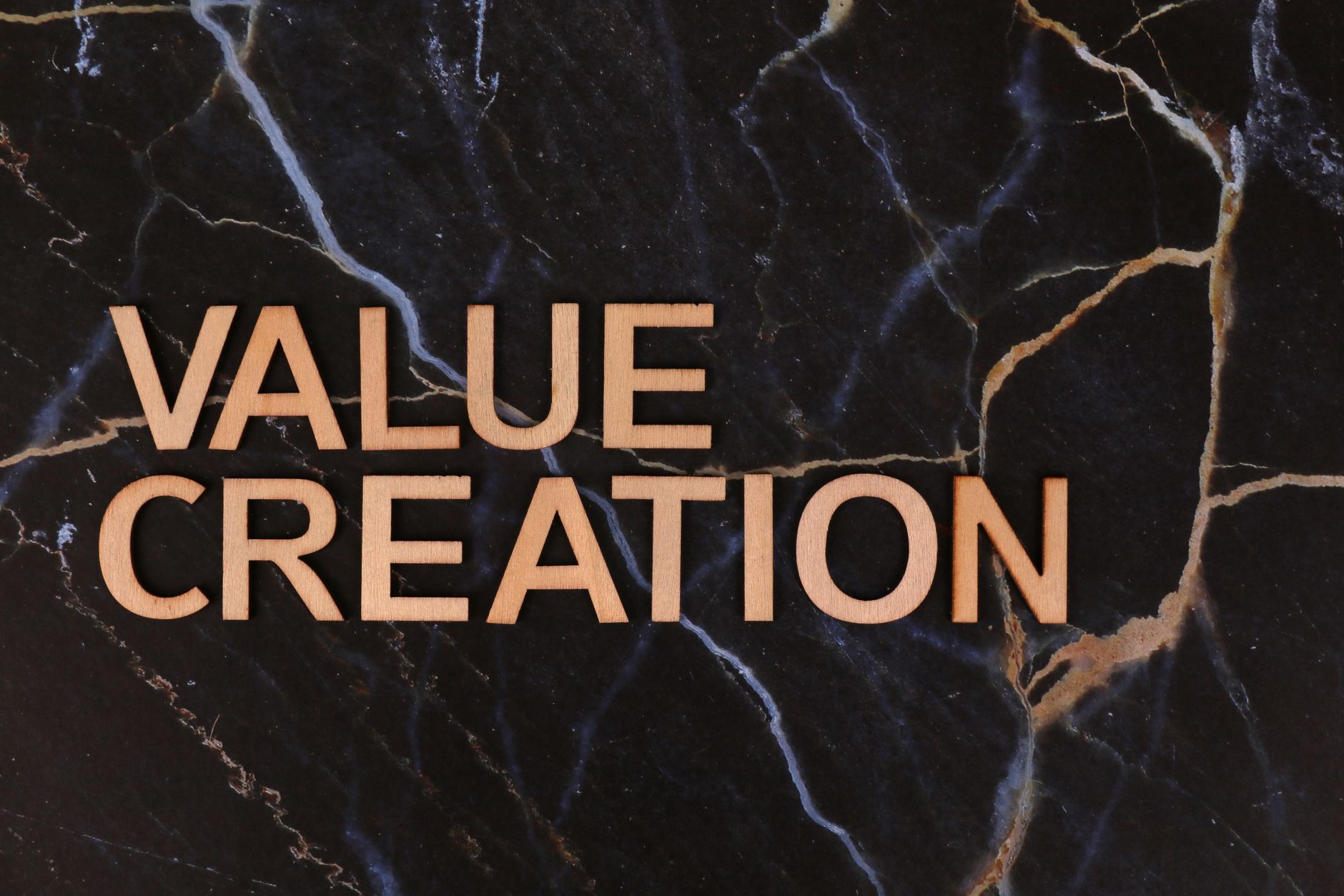 Wooden letters spelling 'Value Creation' on dark marble background, perfect for business themes.