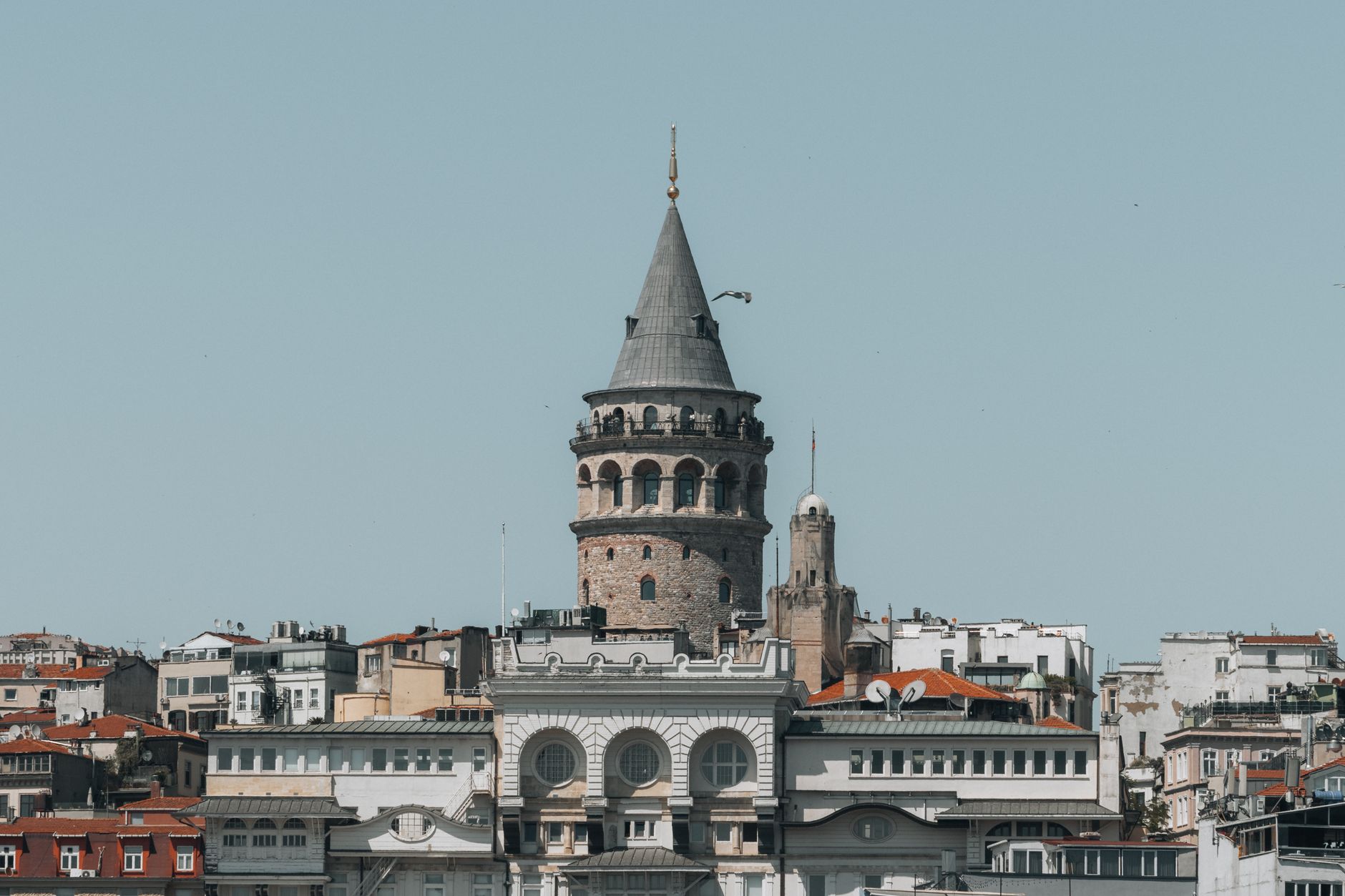 Street view of the Galata Tower in Istanbul, Turkey against a clear blue sky.
