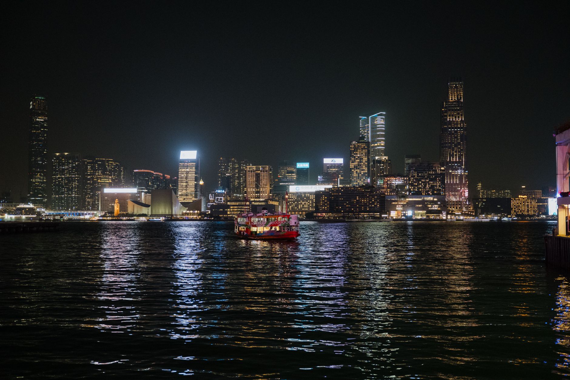 Captivating view of Hong Kong skyline illuminated at night with ferries on Victoria Harbour.