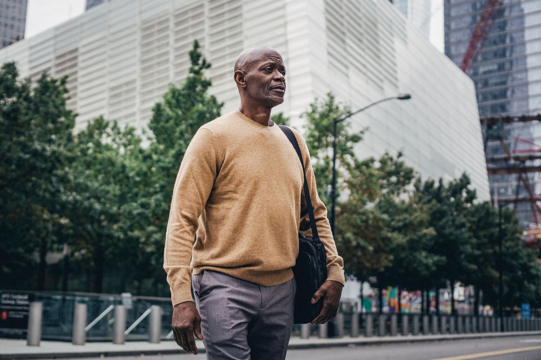 From below of adult African American businessman with personal bag walking in city center