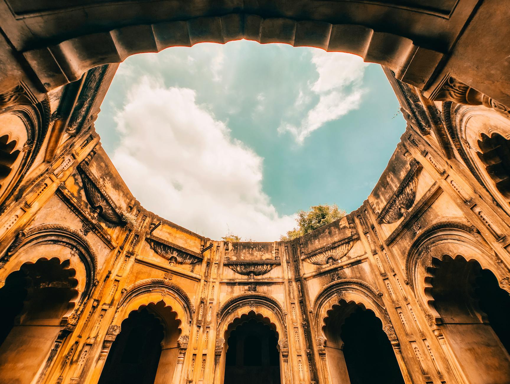 A stunning view of ancient architecture from below, showcasing ornate arches and a bright sky.