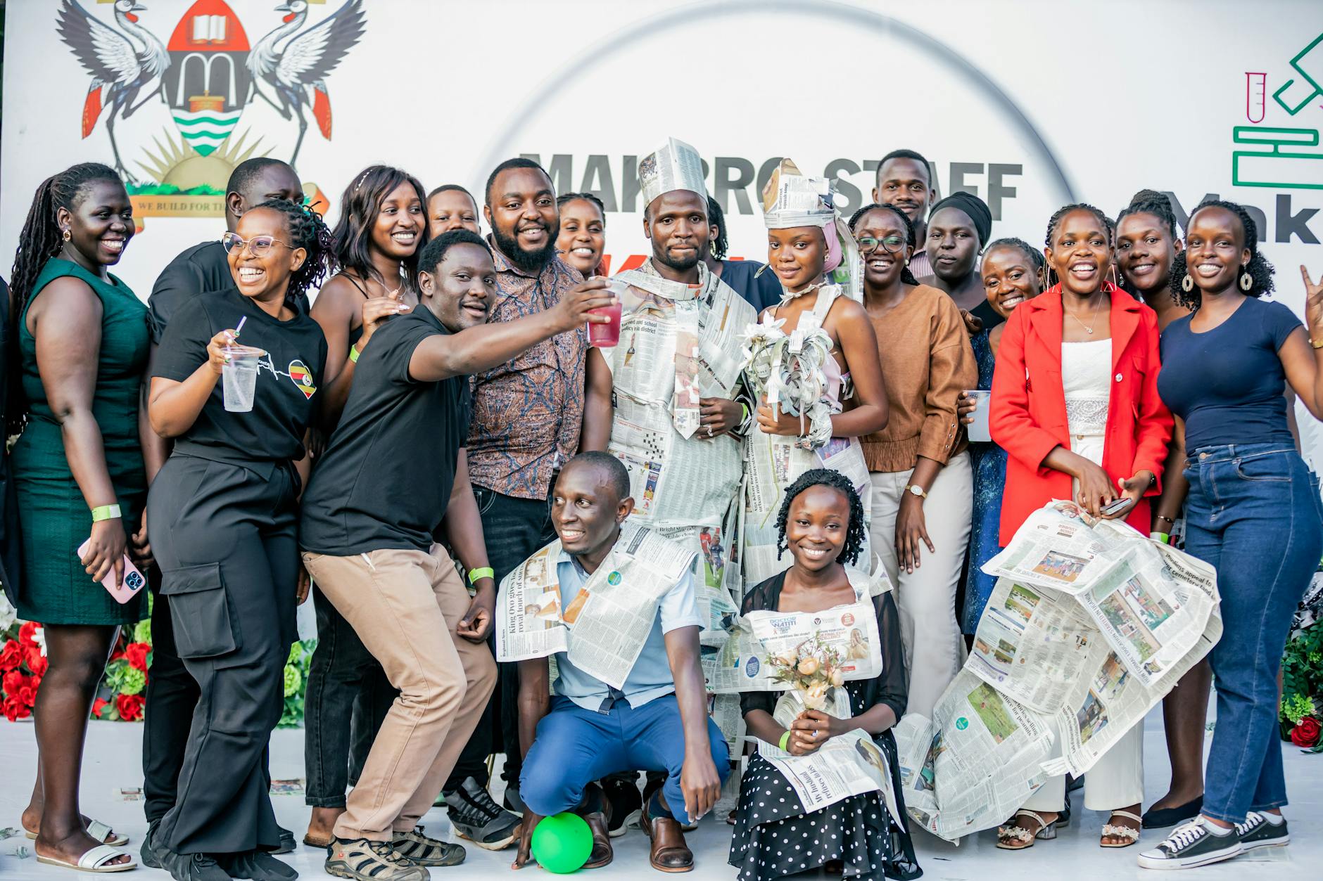 A vibrant gathering of young adults in creative newspaper fashion, enjoying a joyful event.