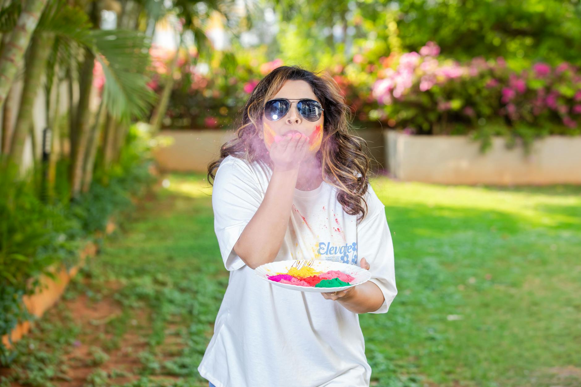 A woman joyfully celebrating Holi outdoors with vibrant colored powder.