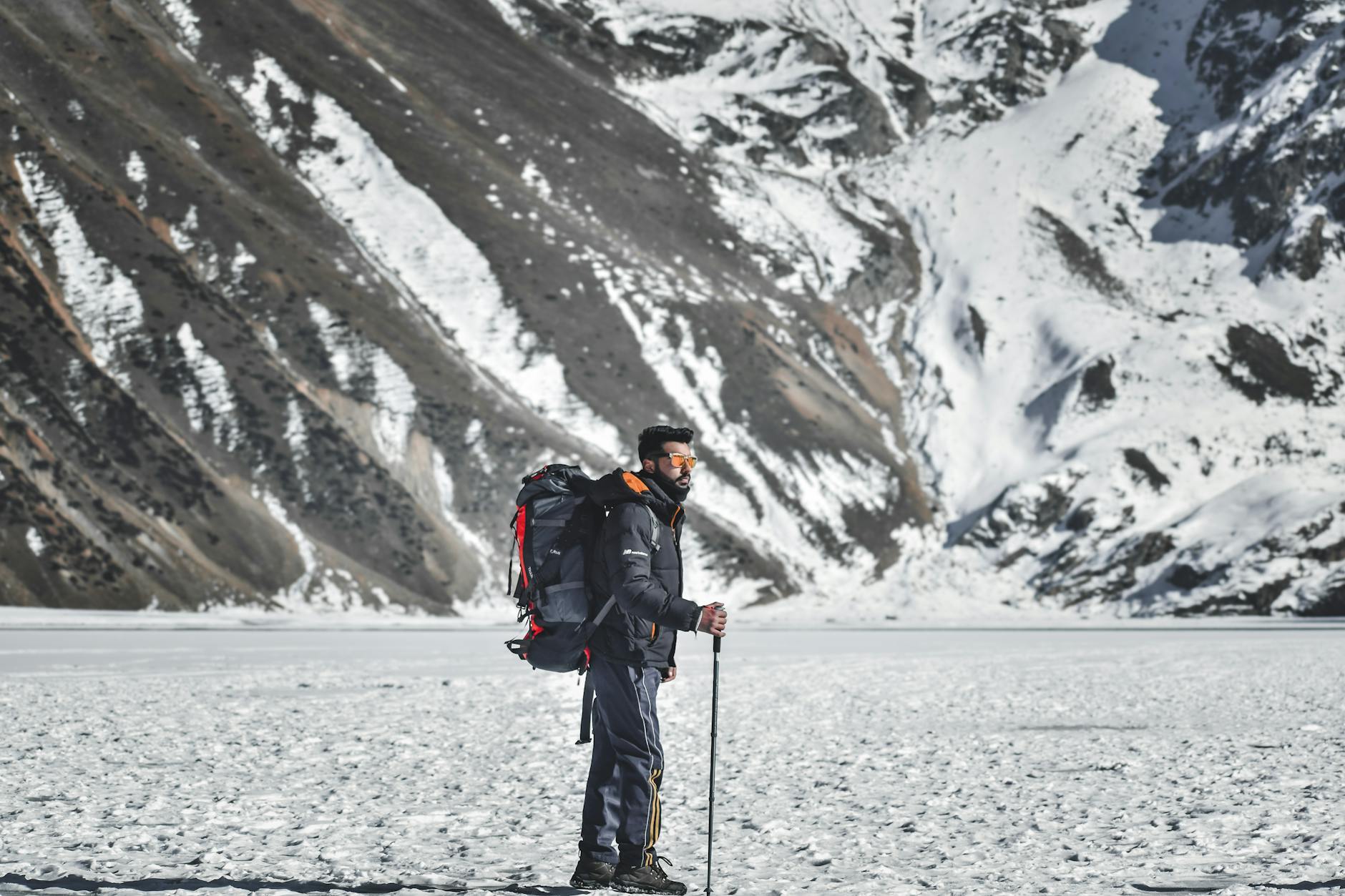 An adventurous hiker traverses a snowy mountain landscape, showcasing pristine winter scenery.