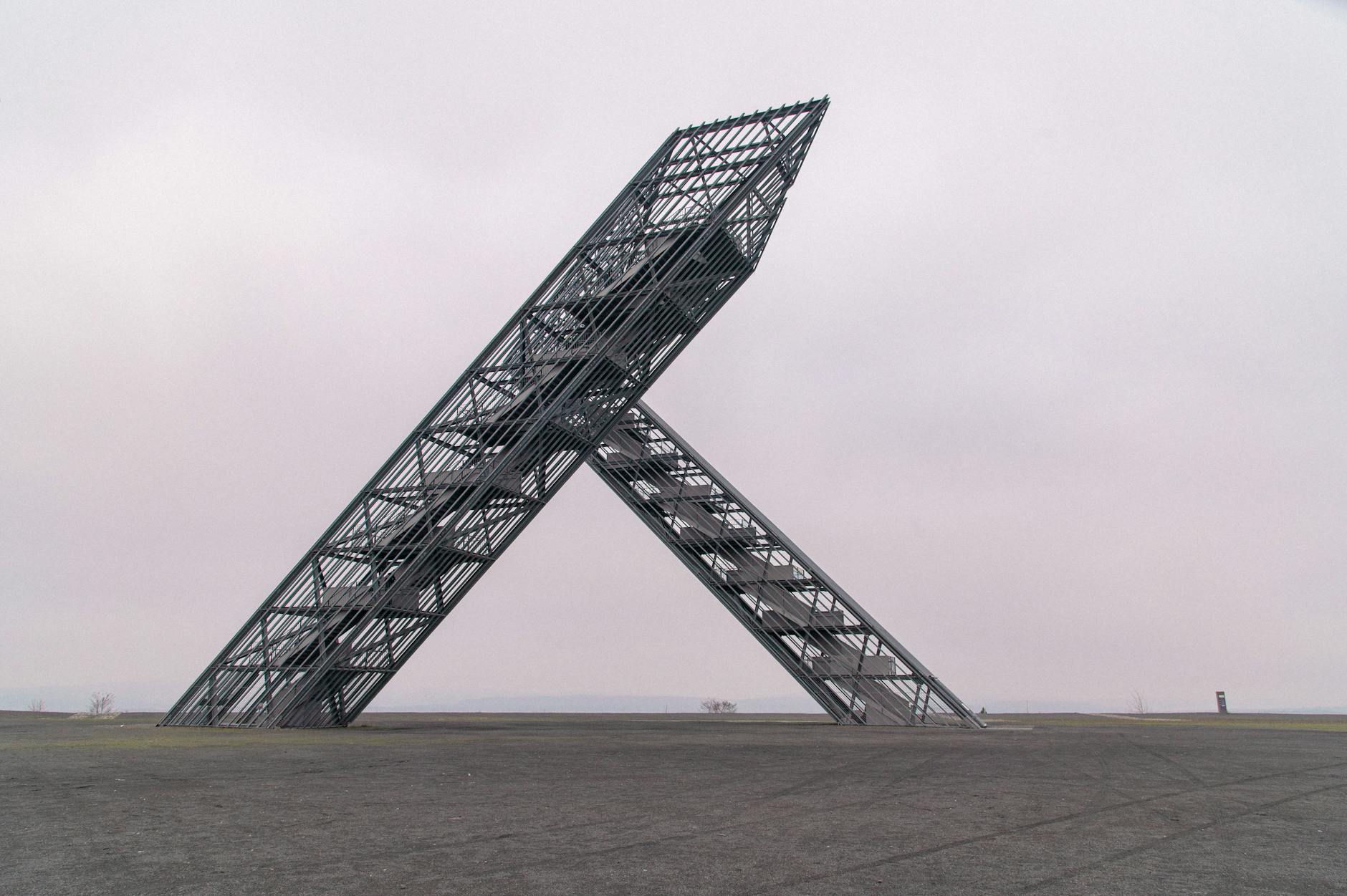 Modern industrial sculpture at Völklingen Ironworks under a cloudy sky.