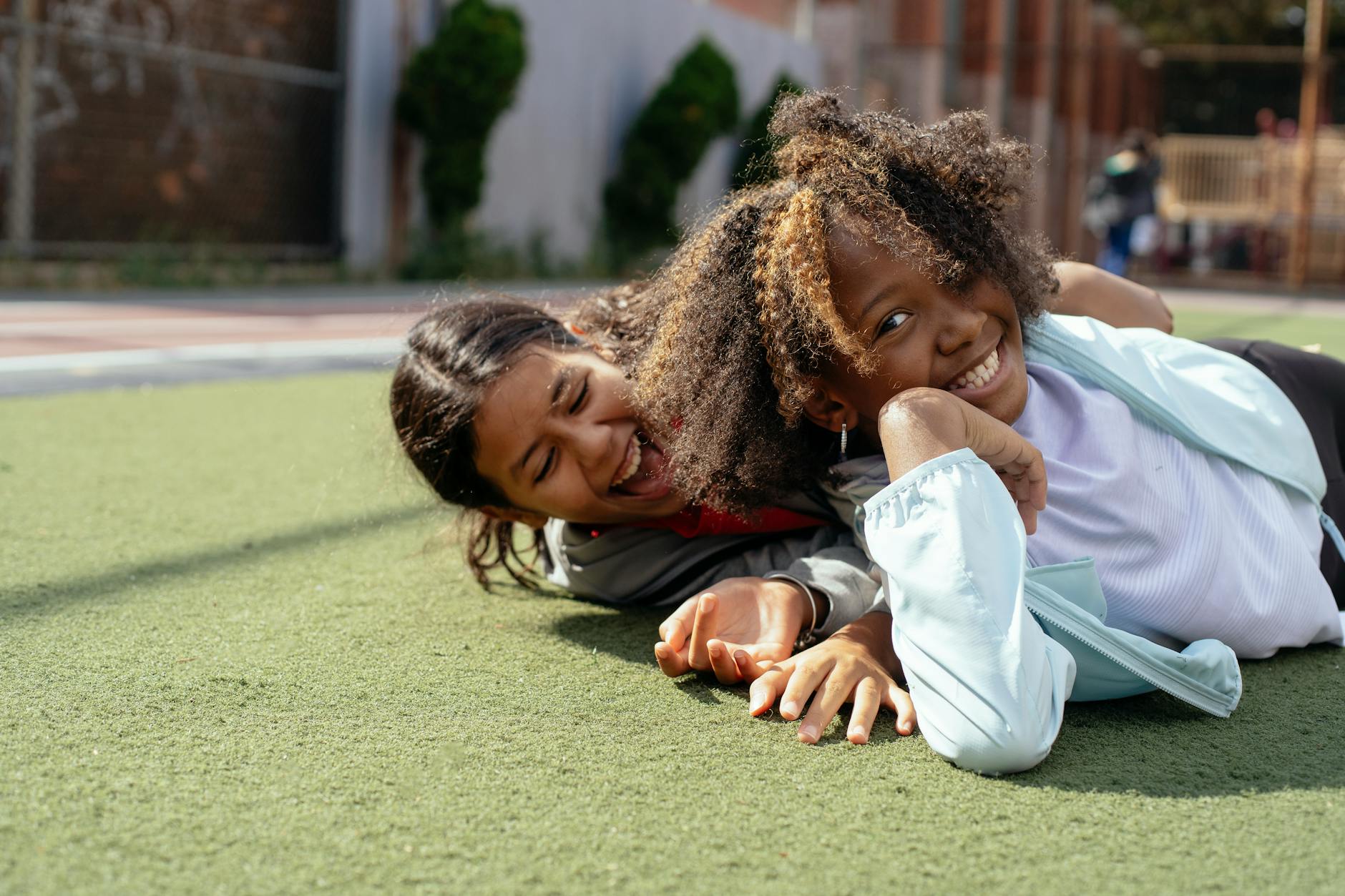 Diverse children in casual clothes lying on sports ground while having fun together during weekend