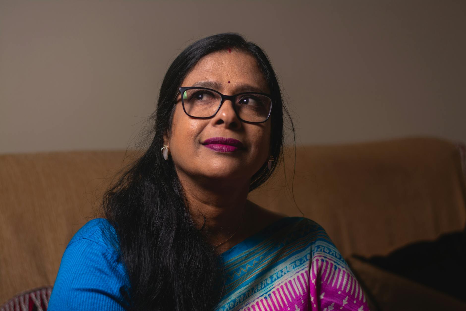 Portrait of an Indian woman wearing a saree, looking thoughtfully upwards.