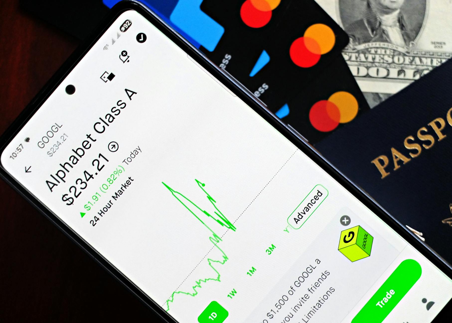 Smartphone displaying stock market app next to U.S. dollar and passport, representing global finance.