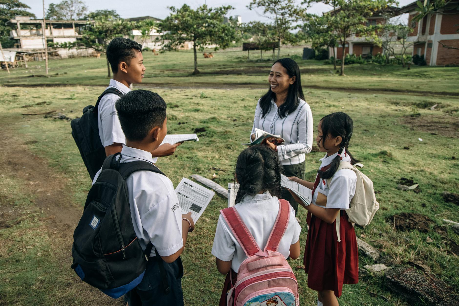 A group of students in school uniforms learning outdoors with their teacher.