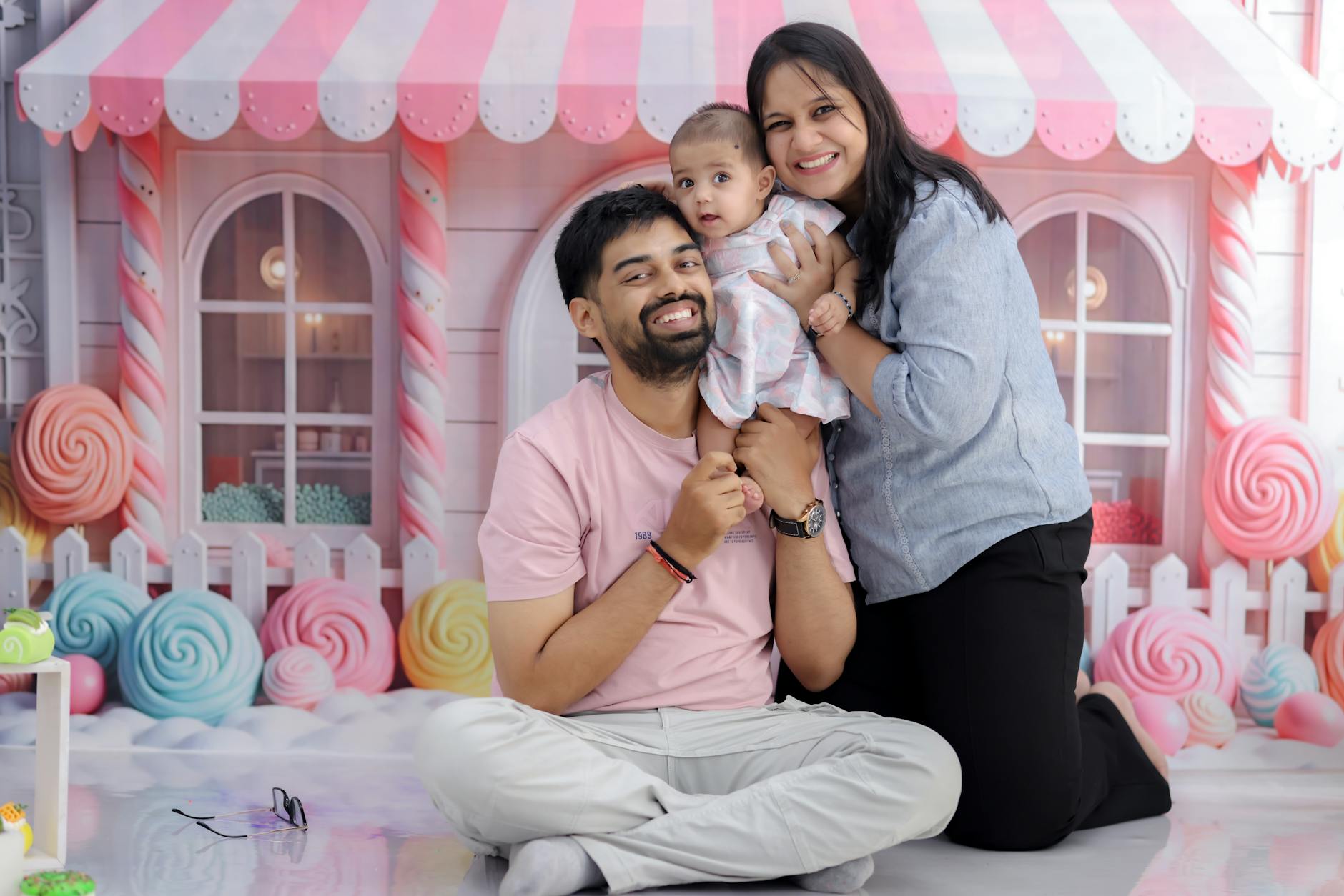 A joyful family posing in a vibrant candy-themed background, capturing a moment of happiness.
