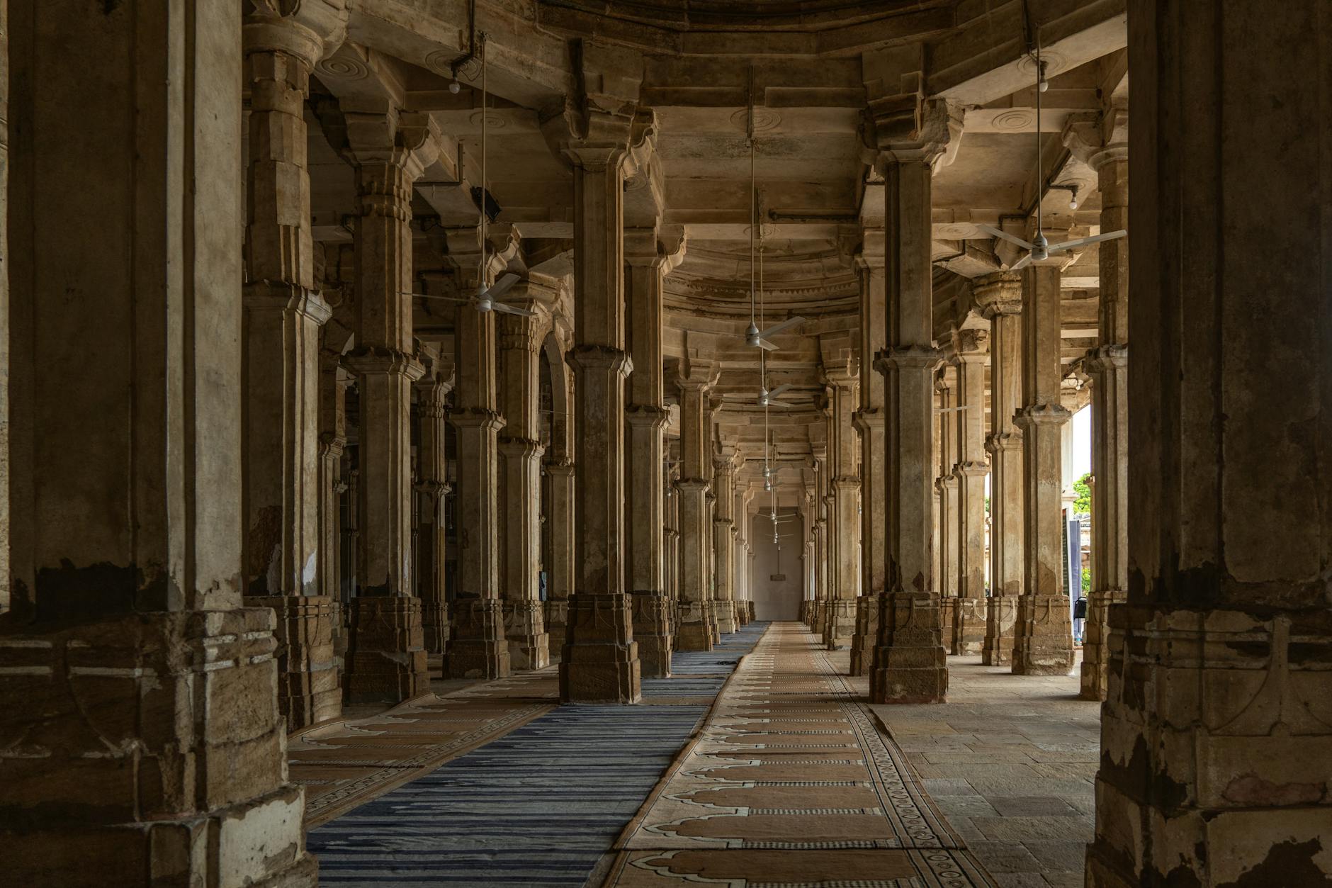 Intricate stone columns and arches in the historic Ahmed Shahi Palace in Ahmedabad, India.