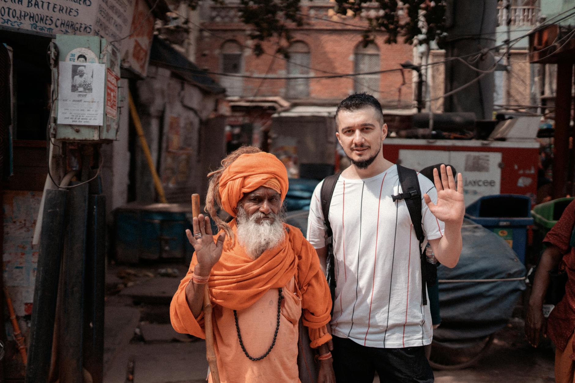 A Hindu sadhu and a visitor pose on the streets of Varanasi, showcasing cultural diversity.