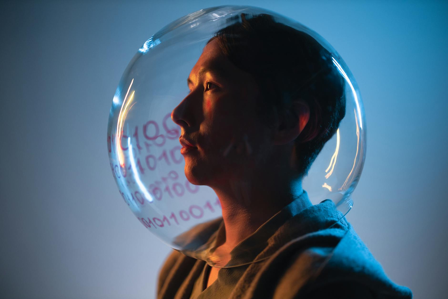 A close-up of a woman wearing a transparent helmet with data symbols, illuminated by blue lighting.