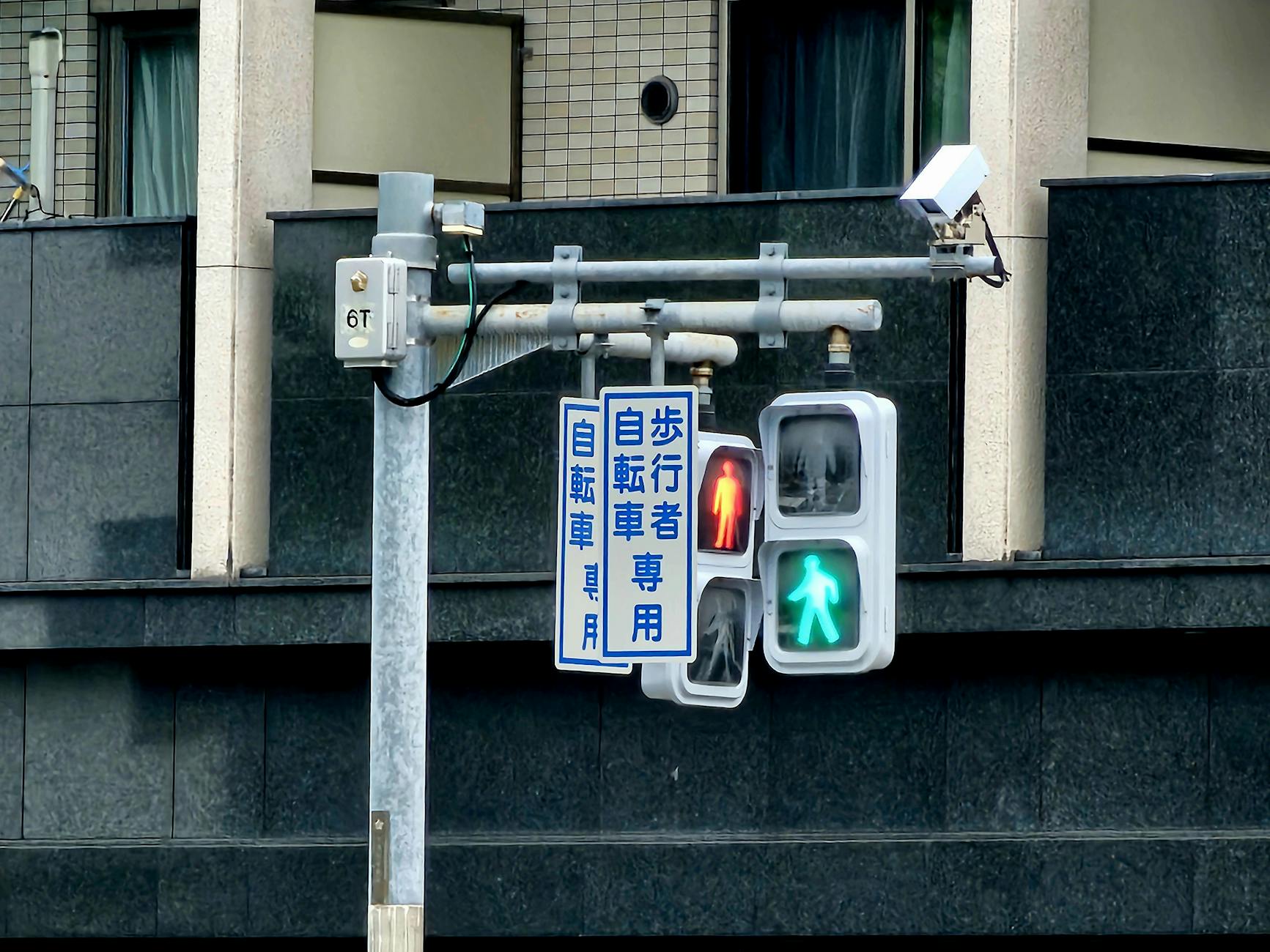 A pedestrian traffic light in Kyoto, Japan, showing green and red signals.