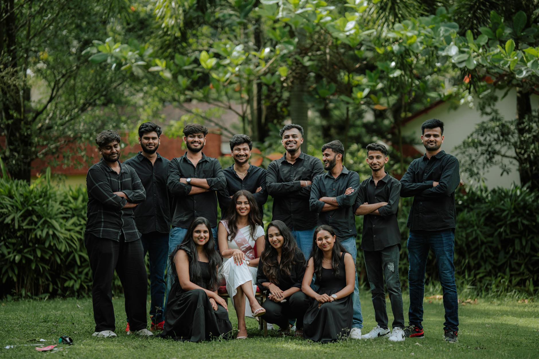 A group of cheerful friends posing together in a lush outdoor garden setting.