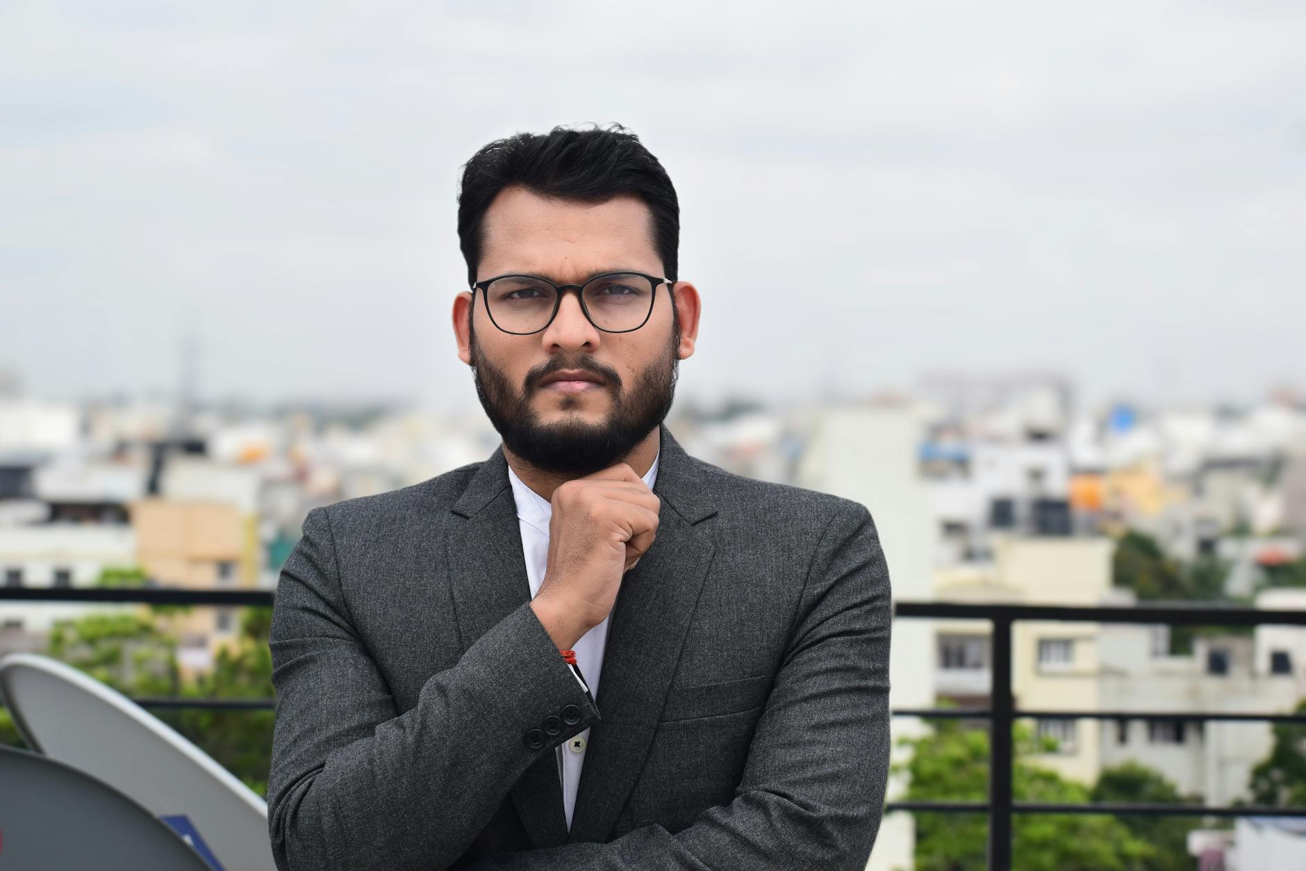 Confident man in business attire standing on an urban rooftop during the day.