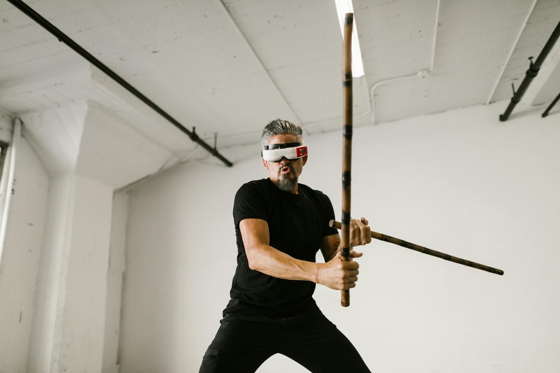 Man practicing arnis with virtual reality headset in a modern indoor setting.