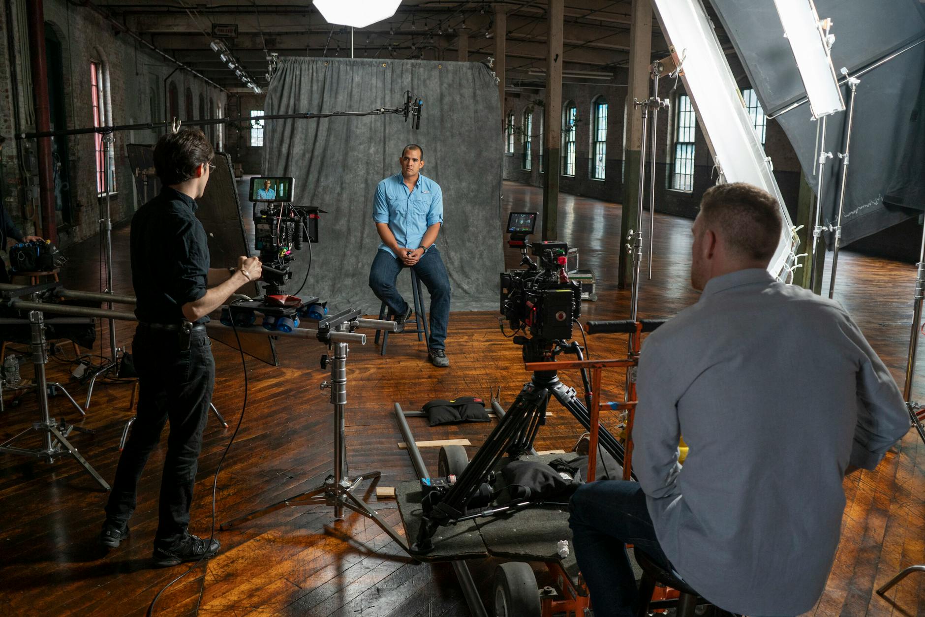 Film crew recording an interview in a Miami studio with professional equipment and lighting.