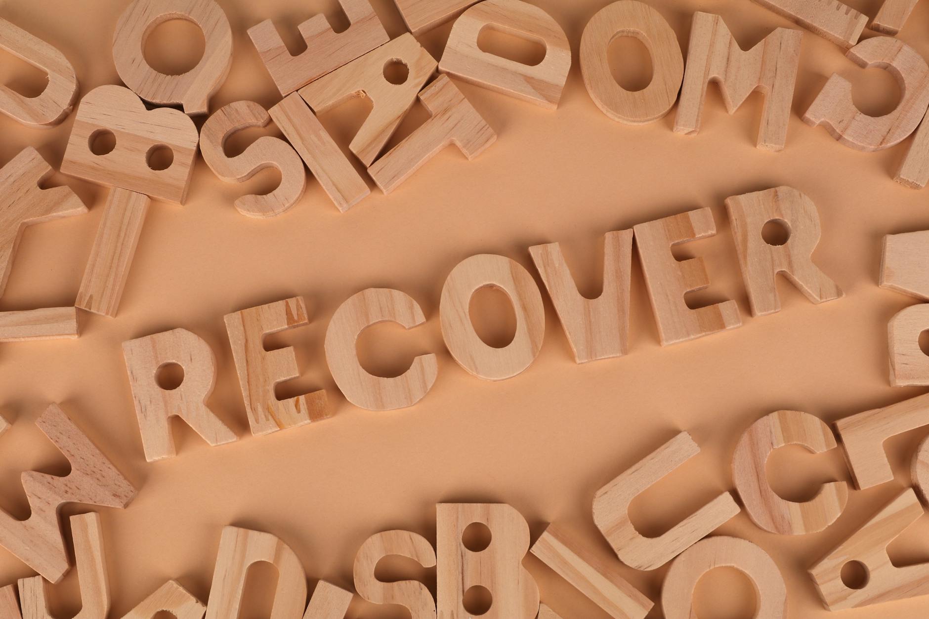 Flat lay of wooden alphabet letters with 'recover' highlighted.