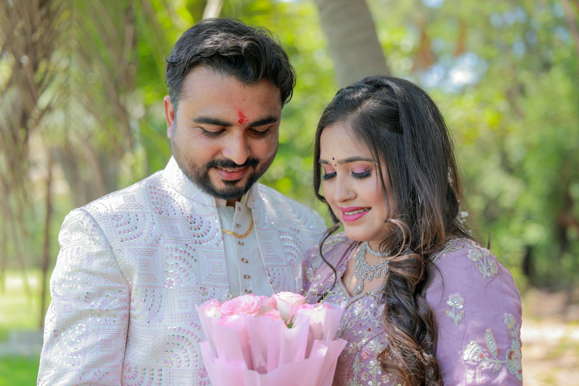 Smiling couple in traditional attire sharing a tender moment in a garden setting.