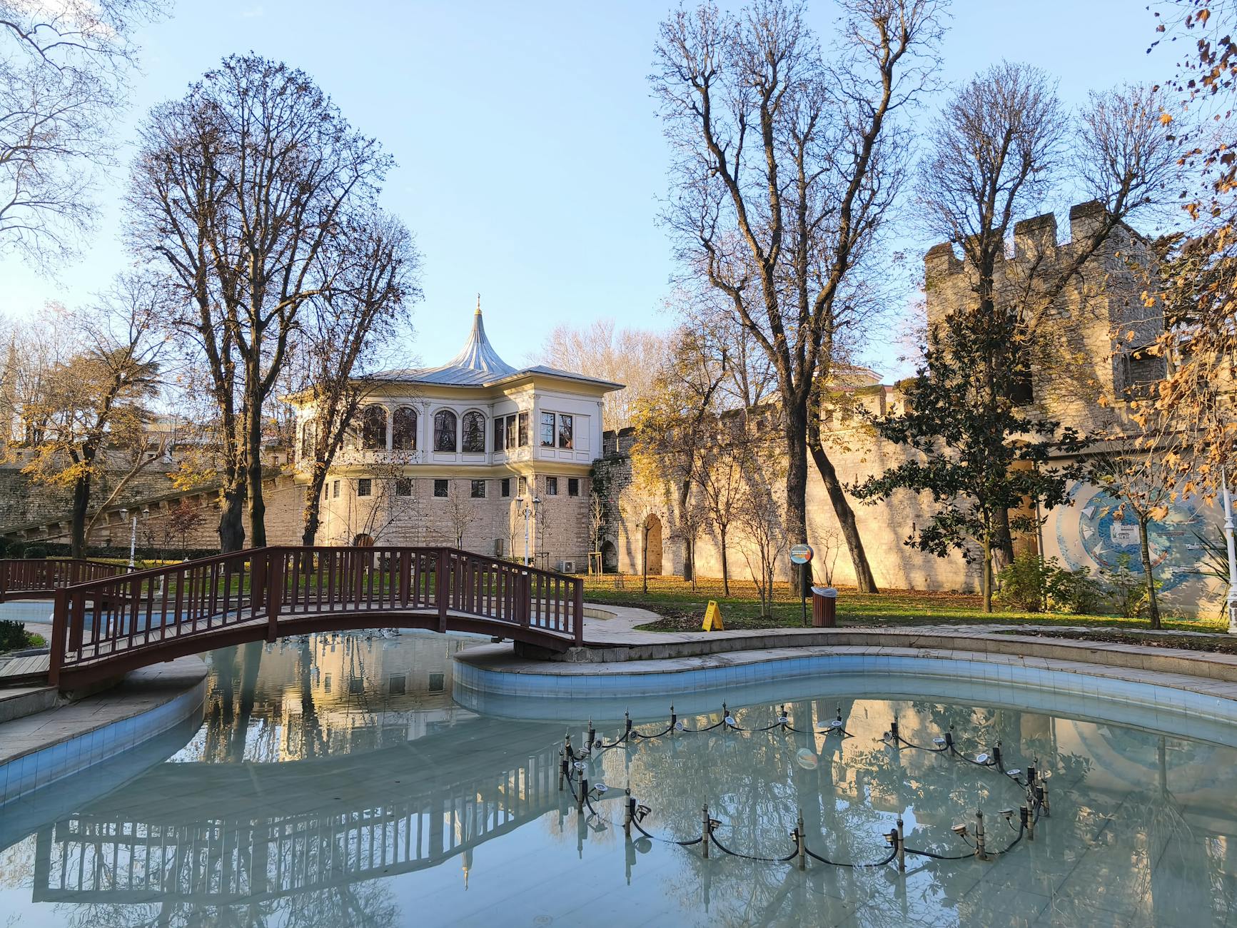 Beautiful garden landscape with bridge and historic castle in autumn.