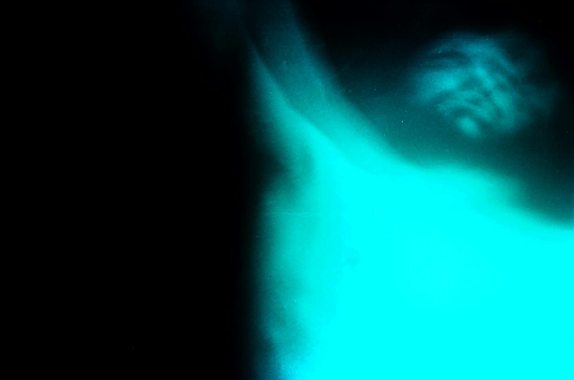 An abstract underwater photo featuring a blurred human figure with striking blue tones creating a mysterious atmosphere.