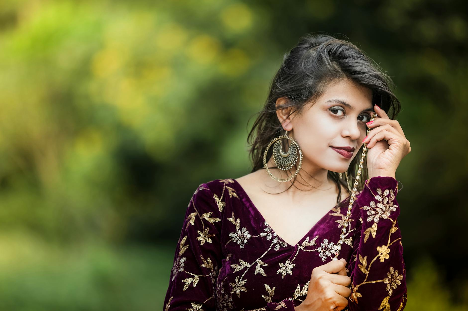 Charming Indian model poses outdoors wearing floral attire and statement earrings.