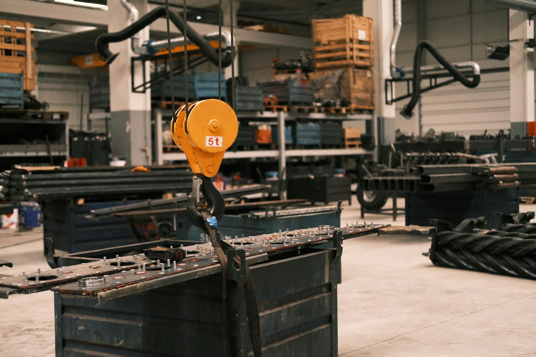 Close-up of a yellow industrial crane hook in a manufacturing workshop in Konya, Türkiye, showcasing metalwork.