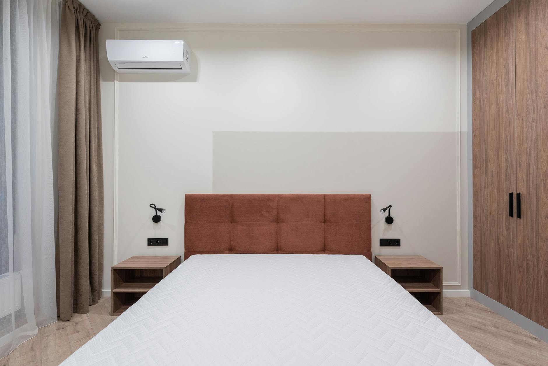 Modern bedroom interior with big comfortable bed and small bedside tables with large wardrobe in apartment