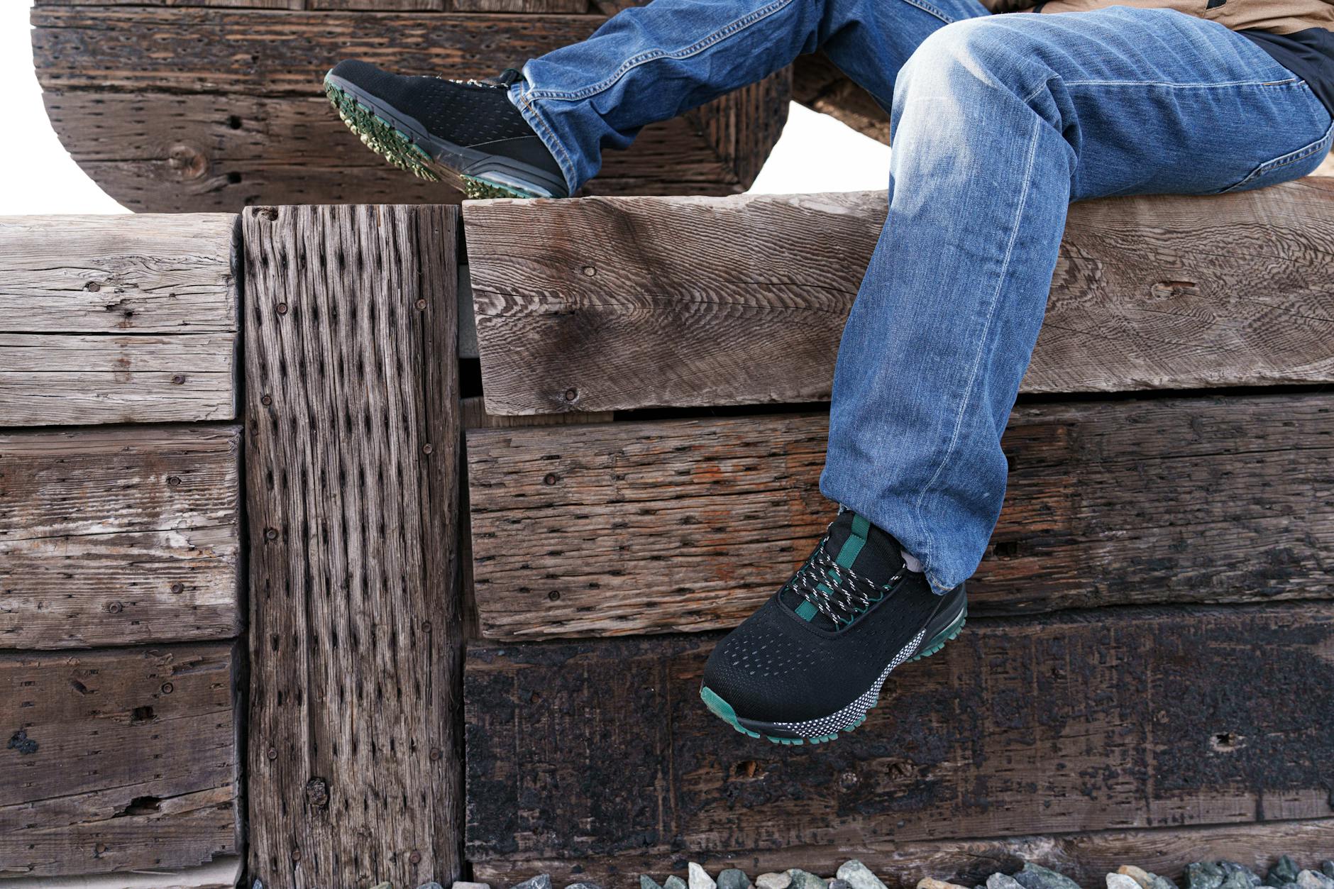 Casual jeans and sneakers resting on a rustic wooden bench, evoking a relaxed outdoor setting.