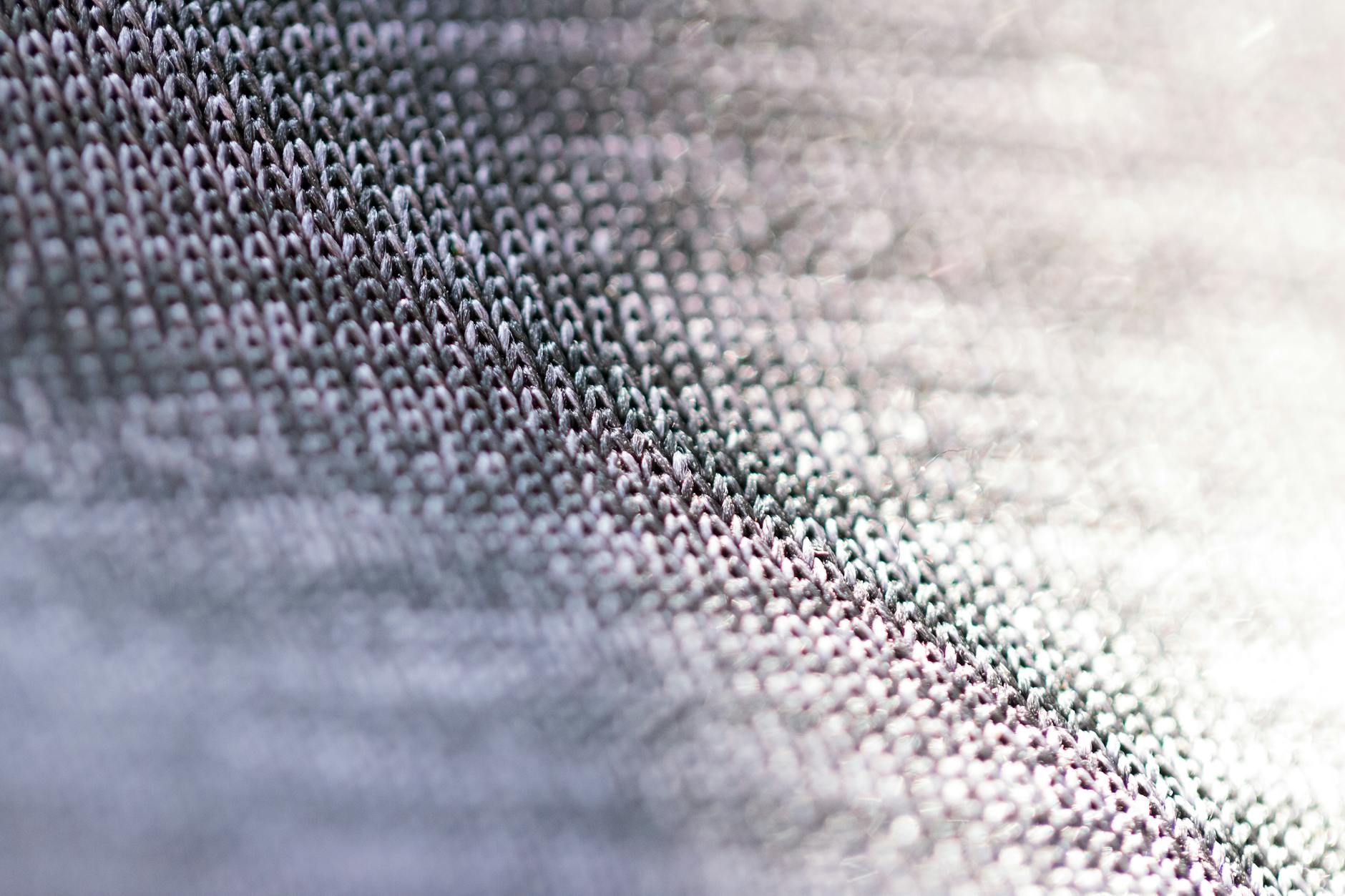 Closeup of fragment of abstract fabric sewn from thin grey threads against blurred background