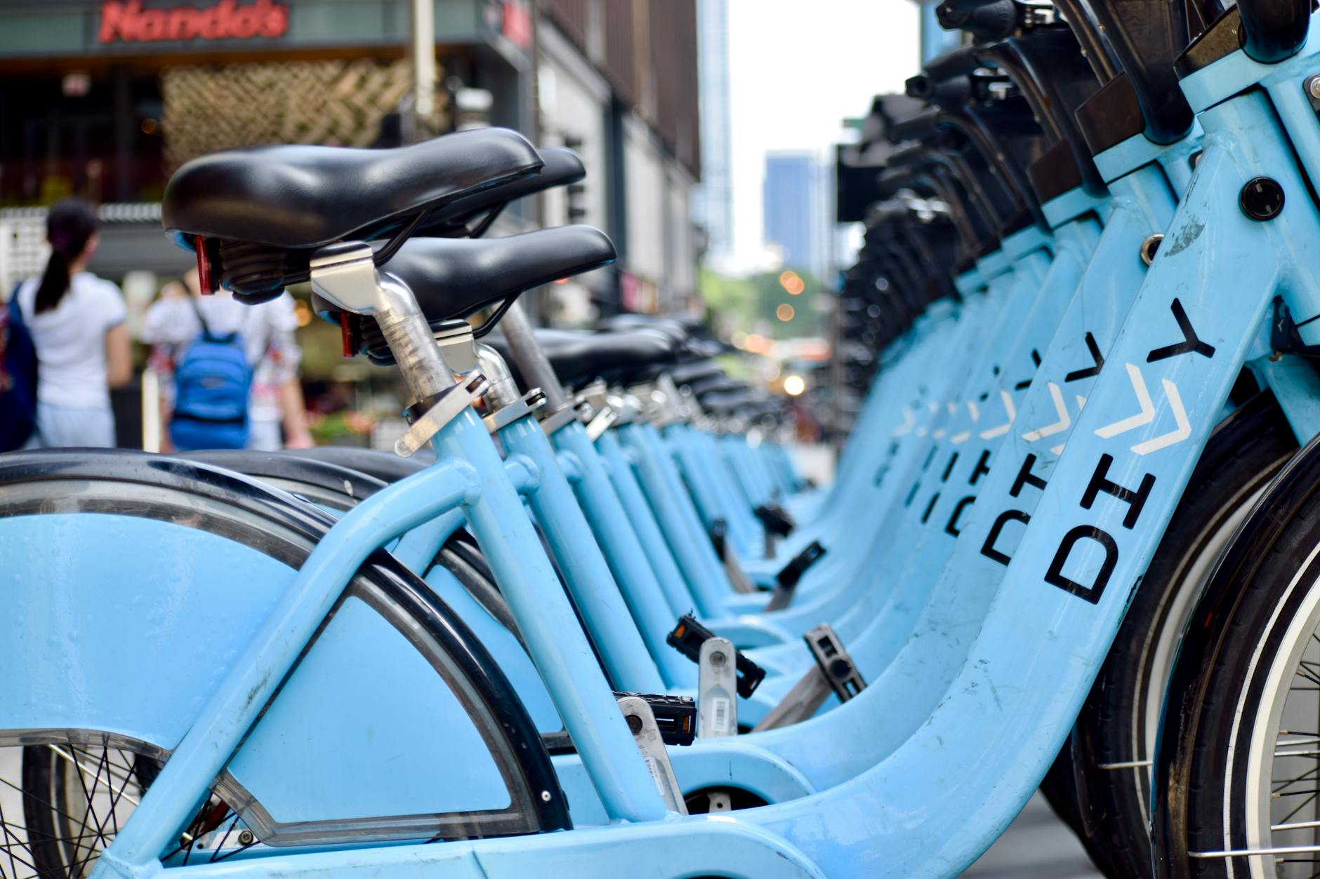 Close-up of blue Divvy bikes lined up outdoors in urban Chicago setting with cityscape.