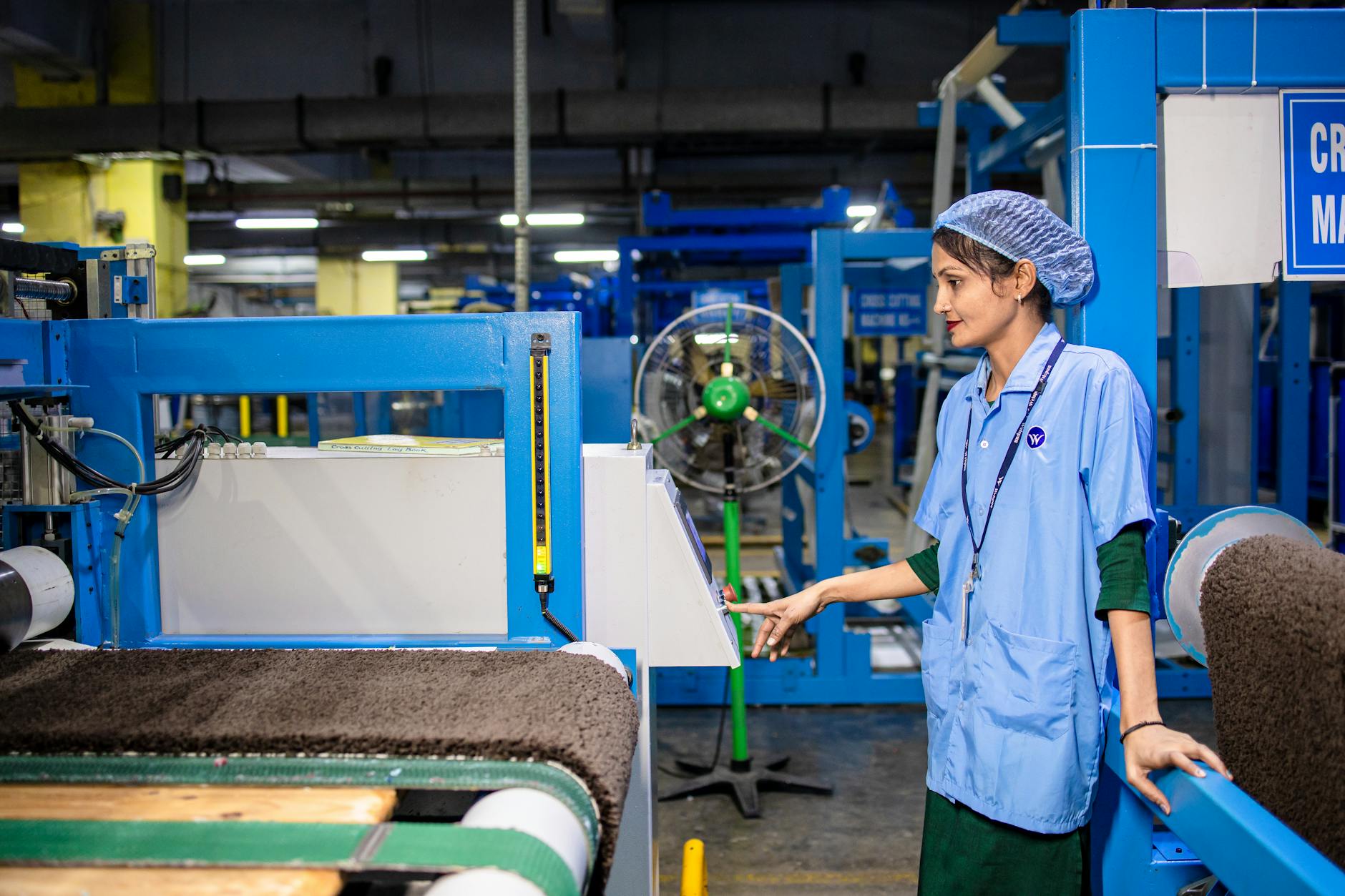 Female worker managing textile machinery in a modern factory setting, highlighting industrial operations.