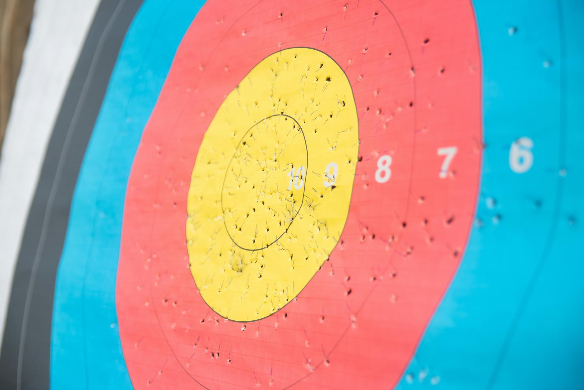 Detailed view of a colorful archery target with numerous arrow holes, showcasing precision