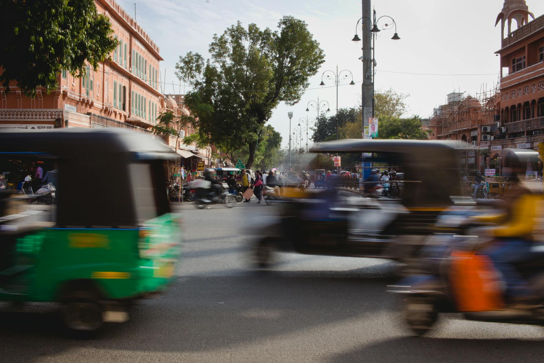 Dynamic snapshot of a busy Jaipur street capturing motion blur of rickshaws and vibrant architecture.
