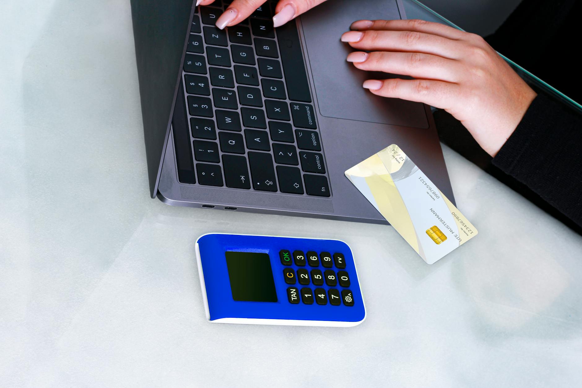 Hands using laptop with card reader for secure online payment. Technology-driven financial transaction.