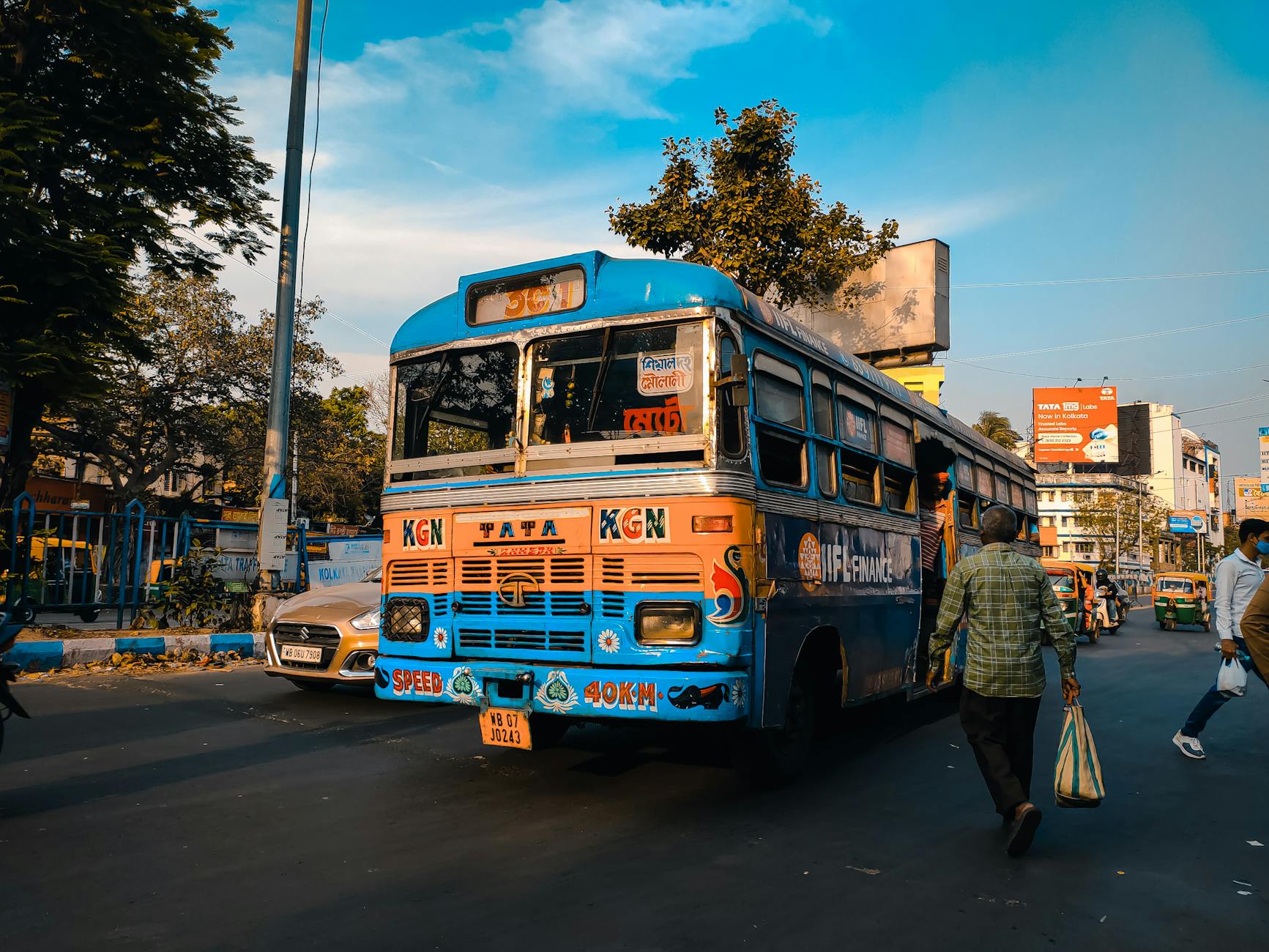 A blue public bus navigating the busy streets of Kolkata, India on a clear day.