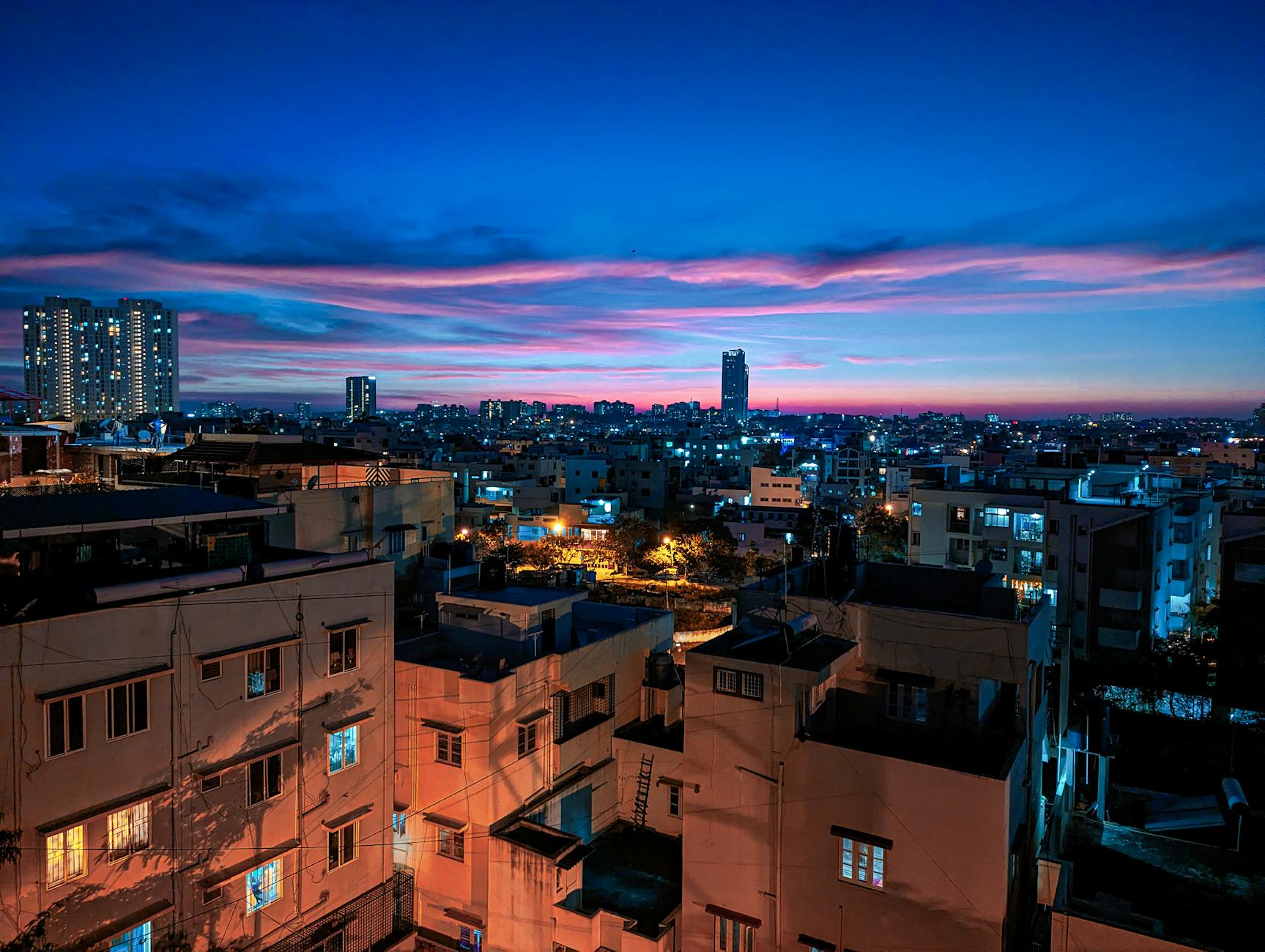 Stunning view of Bengaluru cityscape illuminated at dusk, showcasing modern architecture under a vivid sunset sky.
