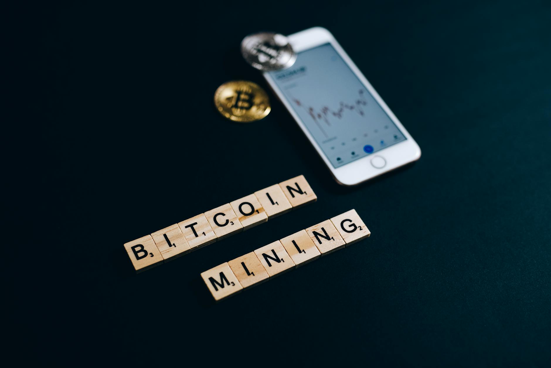 A visual representation of bitcoin mining with smartphone and blockchain concept using Scrabble pieces.