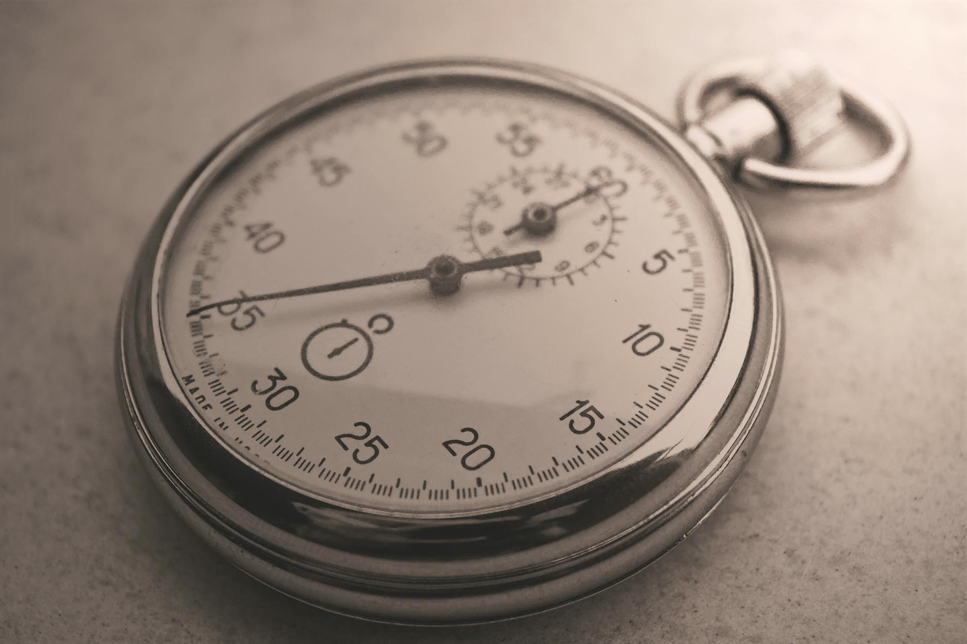 An antique silver pocket watch captured in a sepia tone, showcasing intricate details.