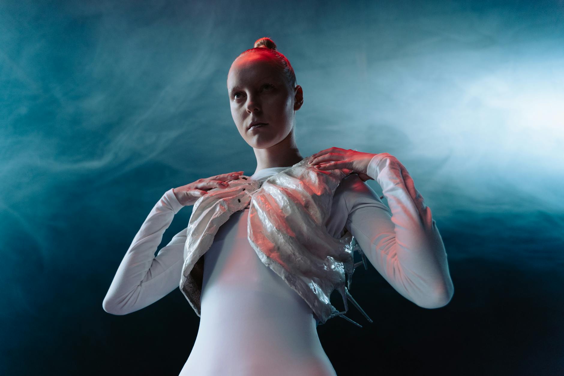 A model in an avant-garde outfit with ethereal lighting and smoke effect, showcasing futuristic fashion.