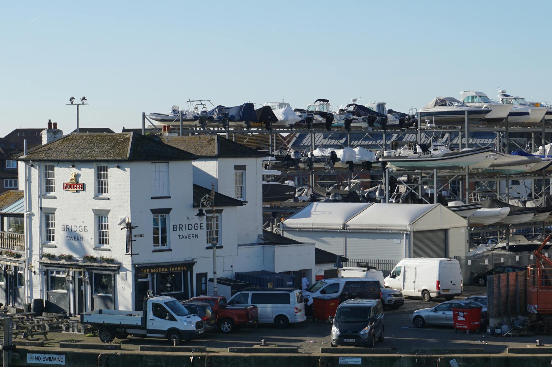 A vibrant scene of Portsmouth harbour with Bridge Tavern and marina filled with docked boats.