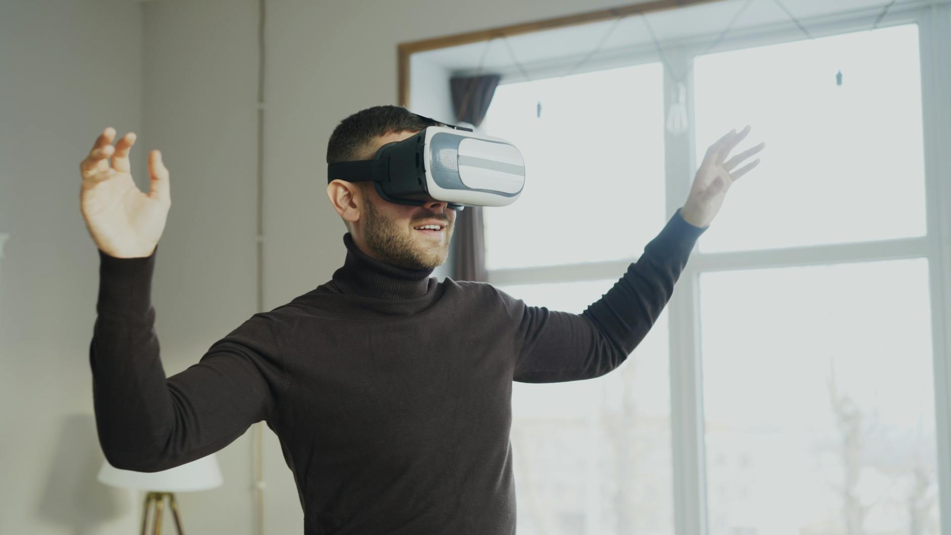 A man using VR goggles, gesturing with excitement indoors.