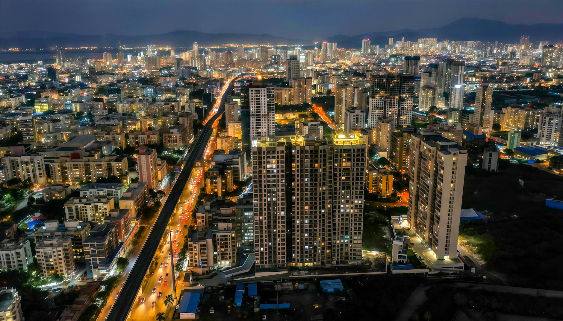 A stunning aerial view of Mumbai's illuminated skyline showcasing high-rise residential towers at night.