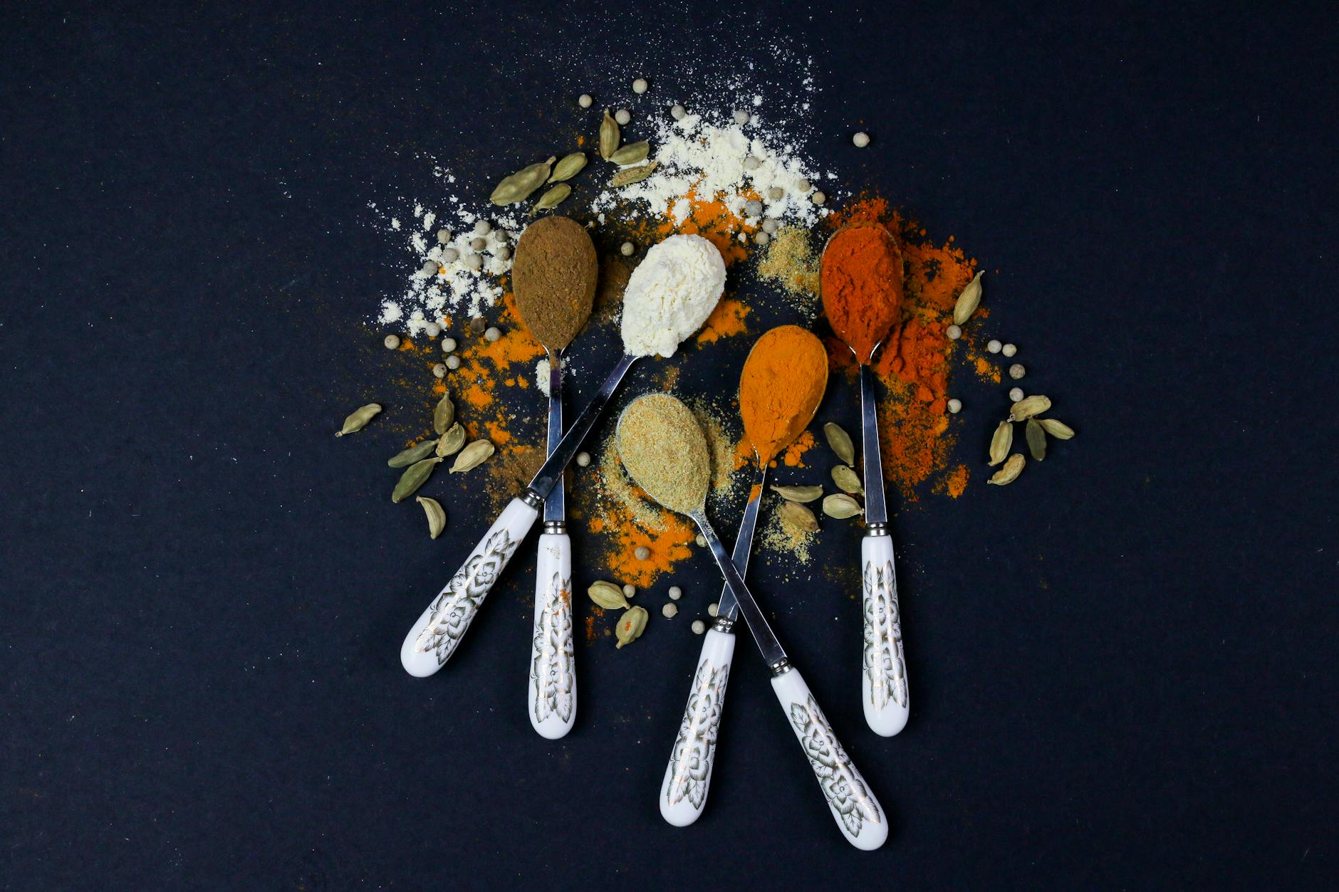 A vibrant assortment of spices on spoons, perfect for culinary themes.