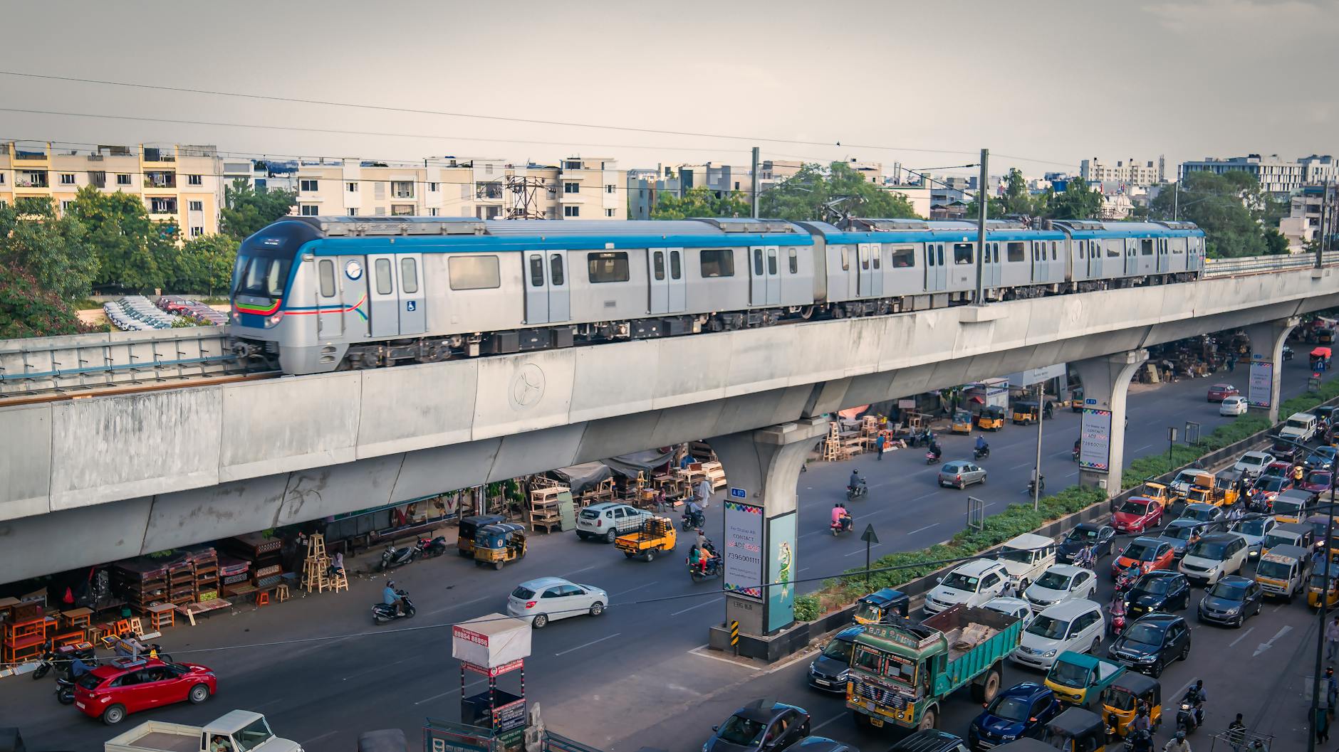 A metro train traverses above city traffic in bustling Hyderabad, India.